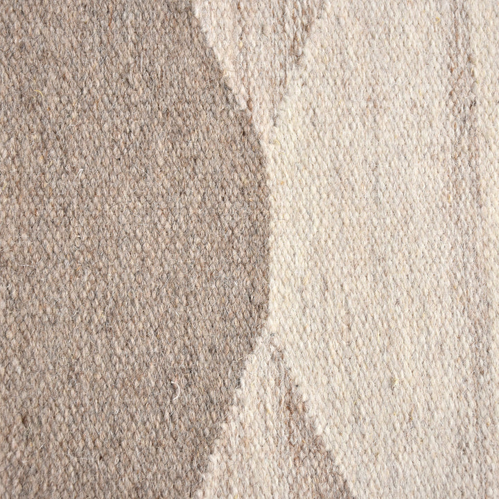 Chhatri handwoven wool rug with bold ivory and beige arch blocks, in a living room