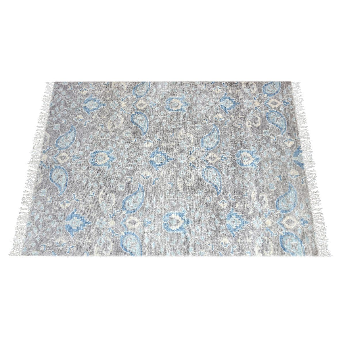 Kairi hand-knotted wool rug with blue paisley on a distressed taupe ground, in a living room