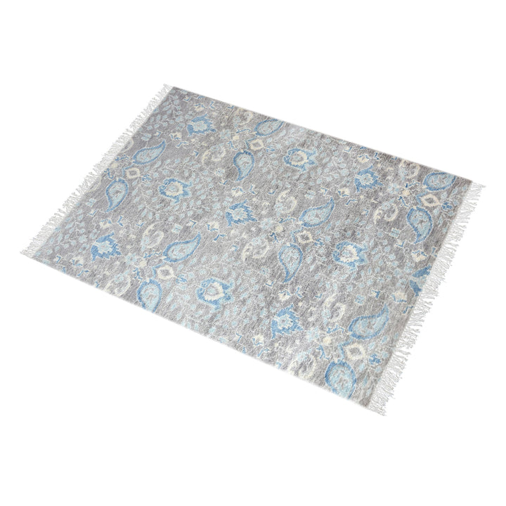 Kairi hand-knotted wool rug with blue paisley on a distressed taupe ground, in a living room