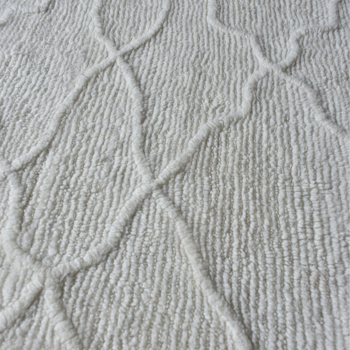 Kangan tufted wool rug with a tonal carved Moroccan lattice in bone ivory, in a bedroom