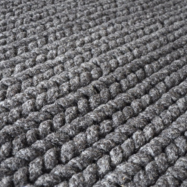 Dor handwoven chunky wool rug in charcoal, woven in thick cords, in a living room