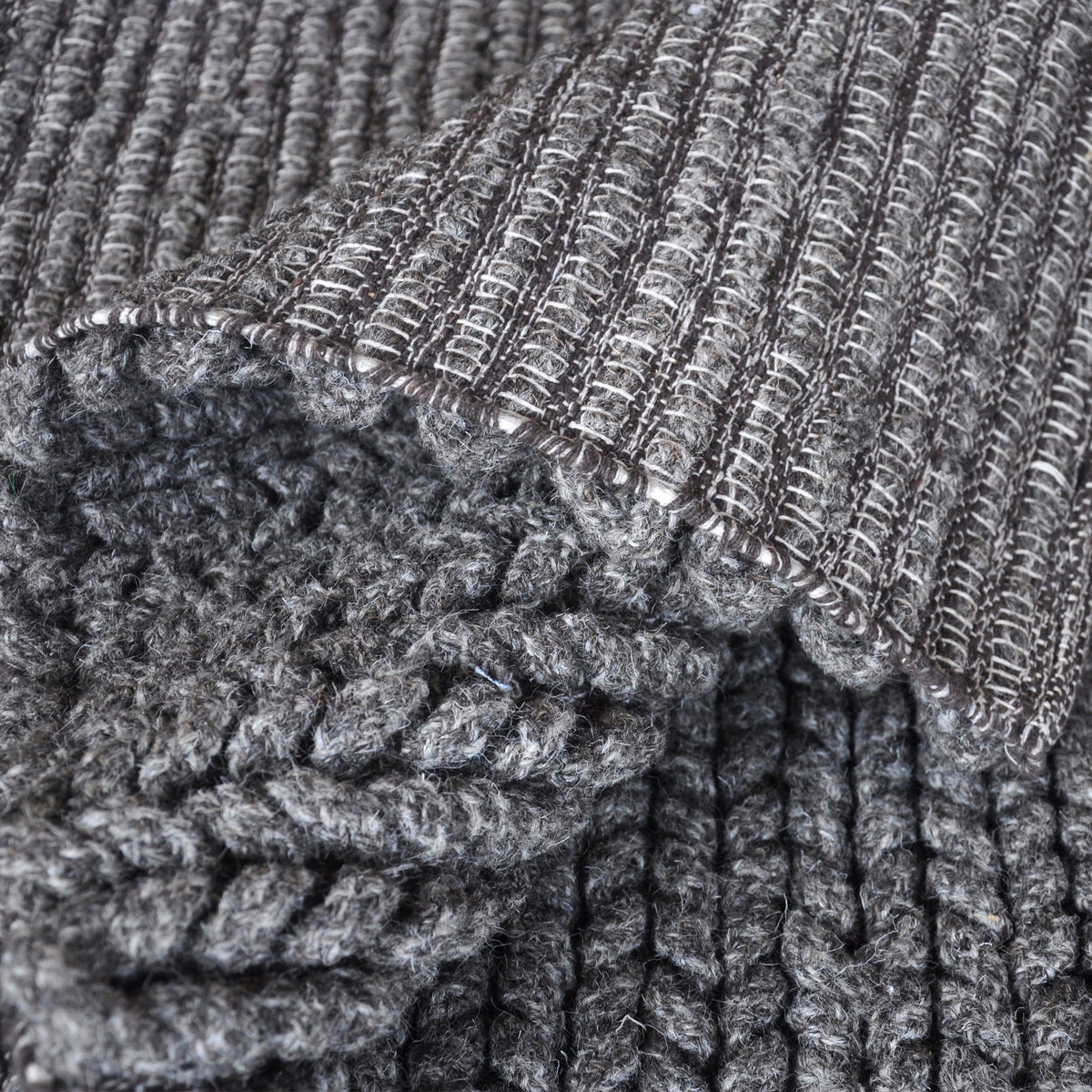 Dor handwoven chunky wool rug in charcoal, woven in thick cords, in a living room