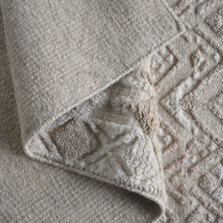 Malai hand-knotted ivory wool rug with a raised diamond lattice, under a dining table