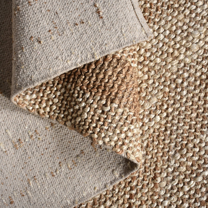 Chaukhat handwoven flatweave jute and wool rug in jute tan with a rust-brown border, in a living room