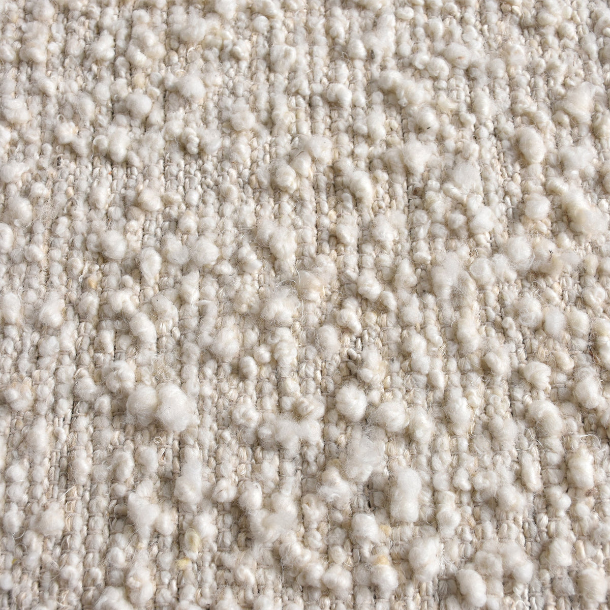 Lambswool handwoven ivory wool and jute rug with a bouclé pebble pile, in a living room