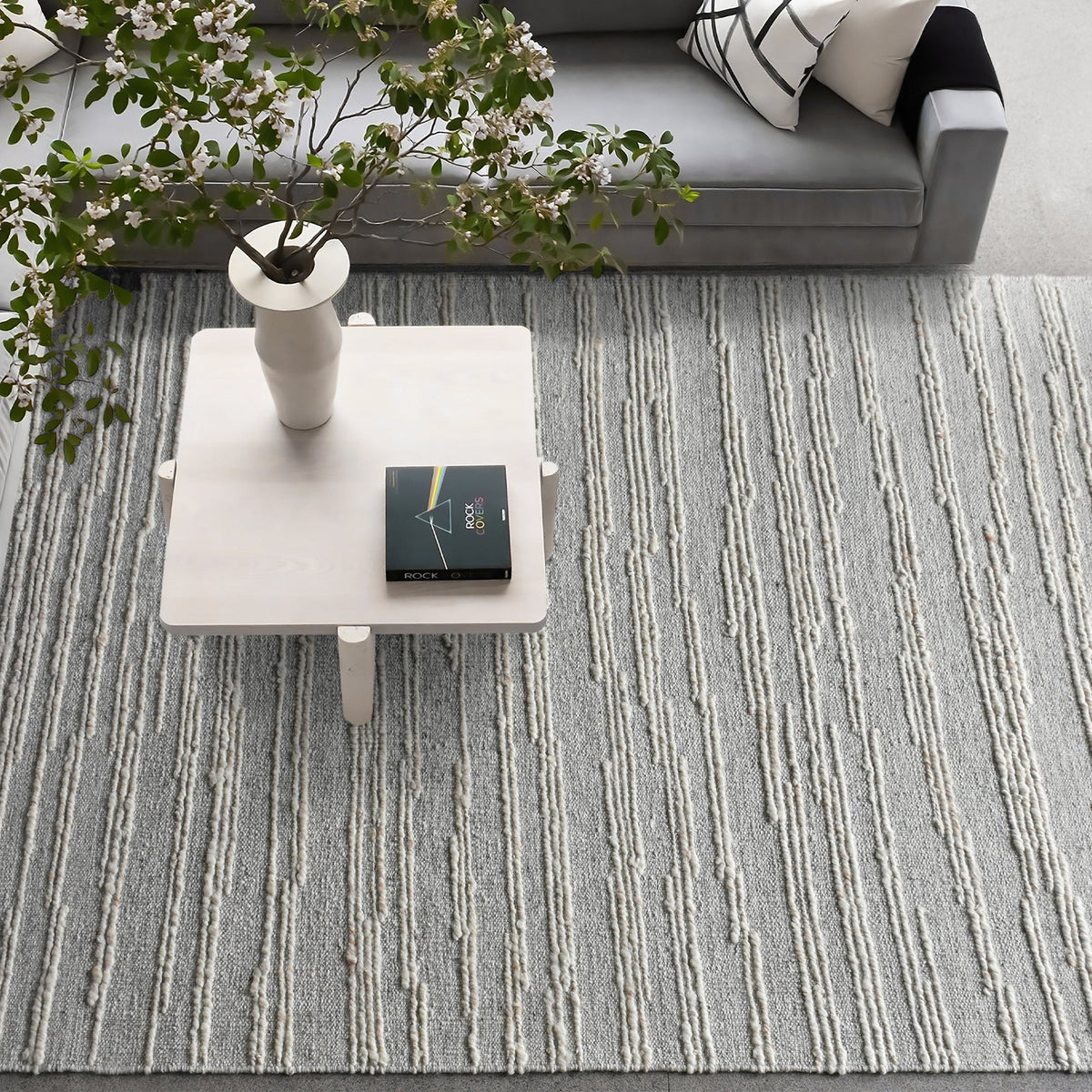 Surma hand-knotted wool rug in slate grey with raised ivory vertical stripes, in a living room