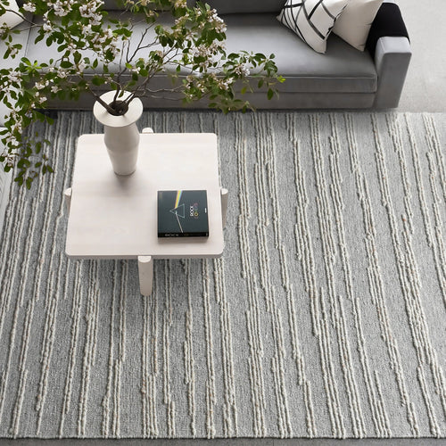 Surma hand-knotted wool rug in slate grey with raised ivory vertical stripes, in a living room