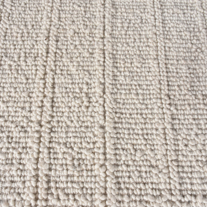 Oon handwoven ribbed wool rug in undyed oatmeal with horizontal ribs, under a coffee table