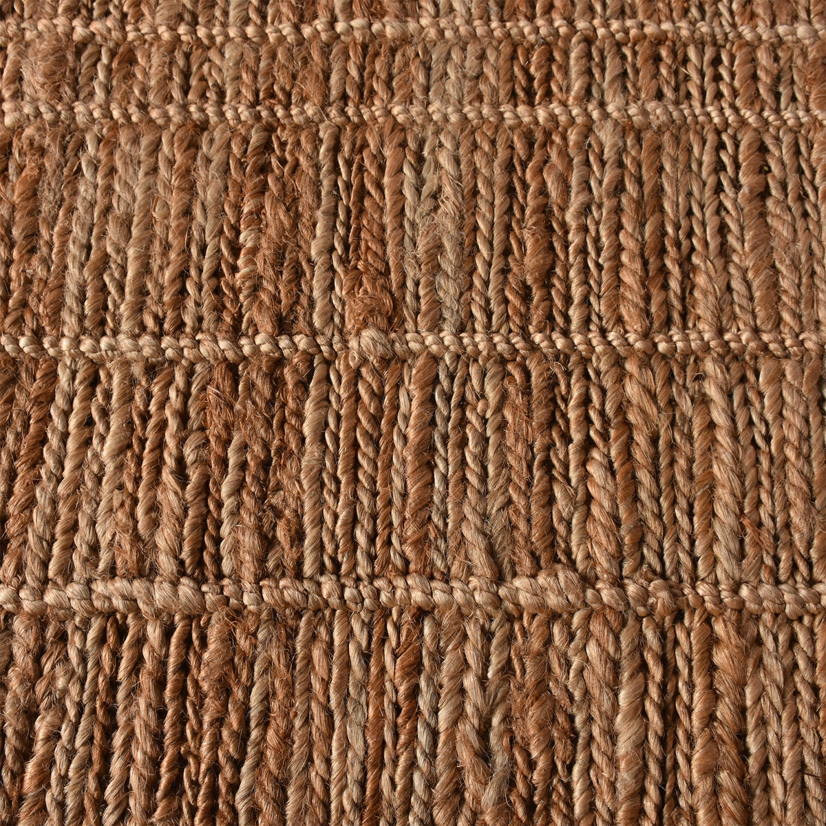 Geru hand-knotted jute rug in burnt sienna and tan with a rustic high pile, in a living room
