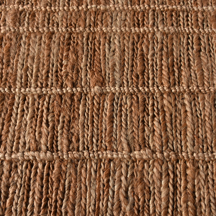 Geru hand-knotted jute rug in burnt sienna and tan with a rustic high pile, in a living room