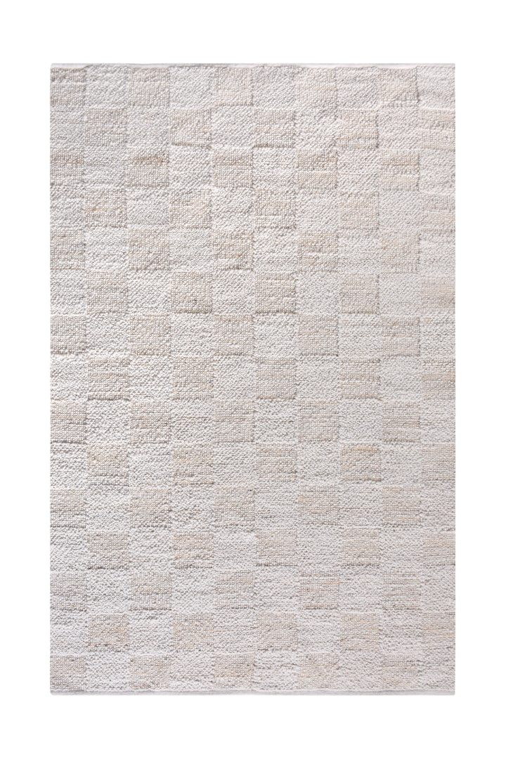 Chaupar handwoven wool and jute rug in greige and ivory with a checkerboard patch texture, in a study