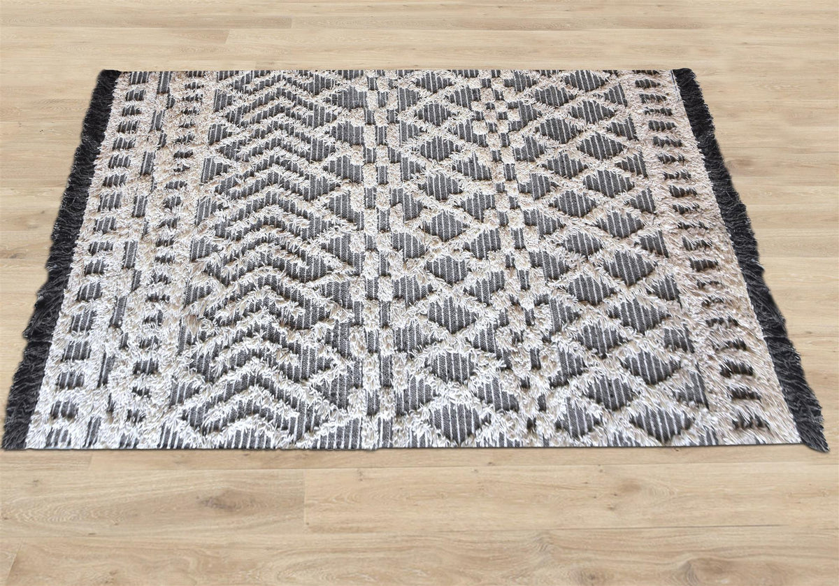 Tassel tufted wool rug with charcoal and ivory chevrons and shaggy bands, in a bedroom