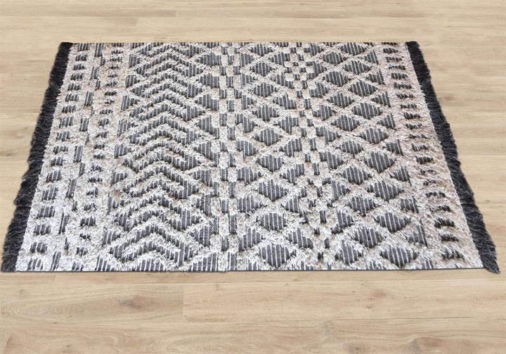 Tassel tufted wool rug with charcoal and ivory chevrons and shaggy bands, in a bedroom