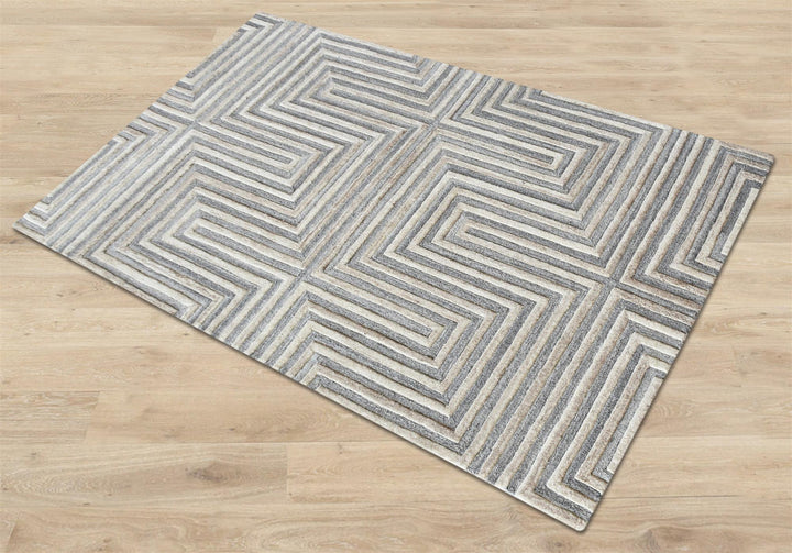 Raasta hand-tufted sand beige wool rug with carved concentric maze lines, in a living room
