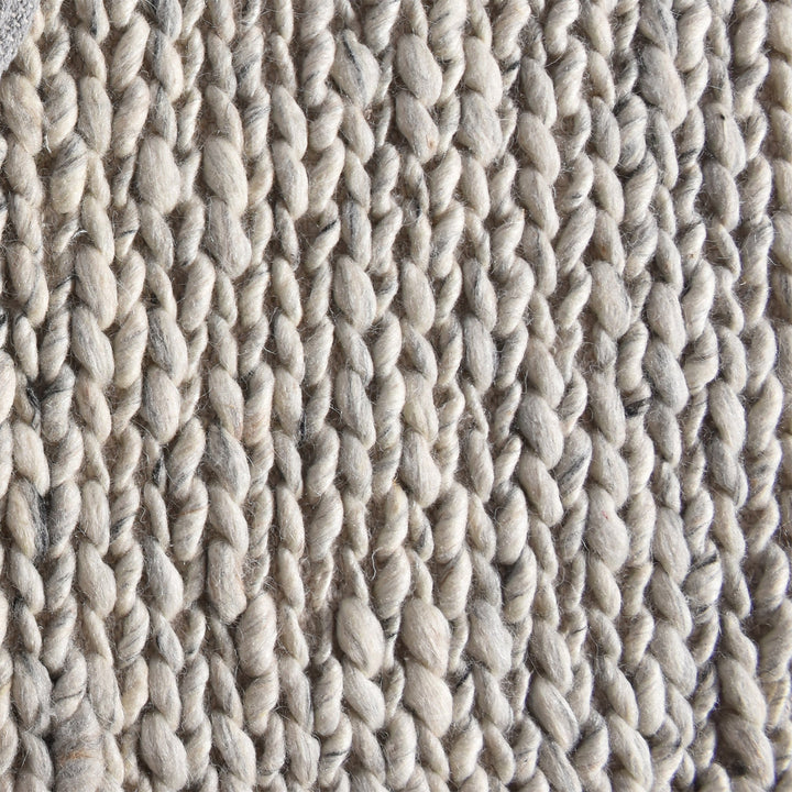 Rassi handwoven wool rug with a chunky braided weave in ivory, oatmeal and grey, in a living room