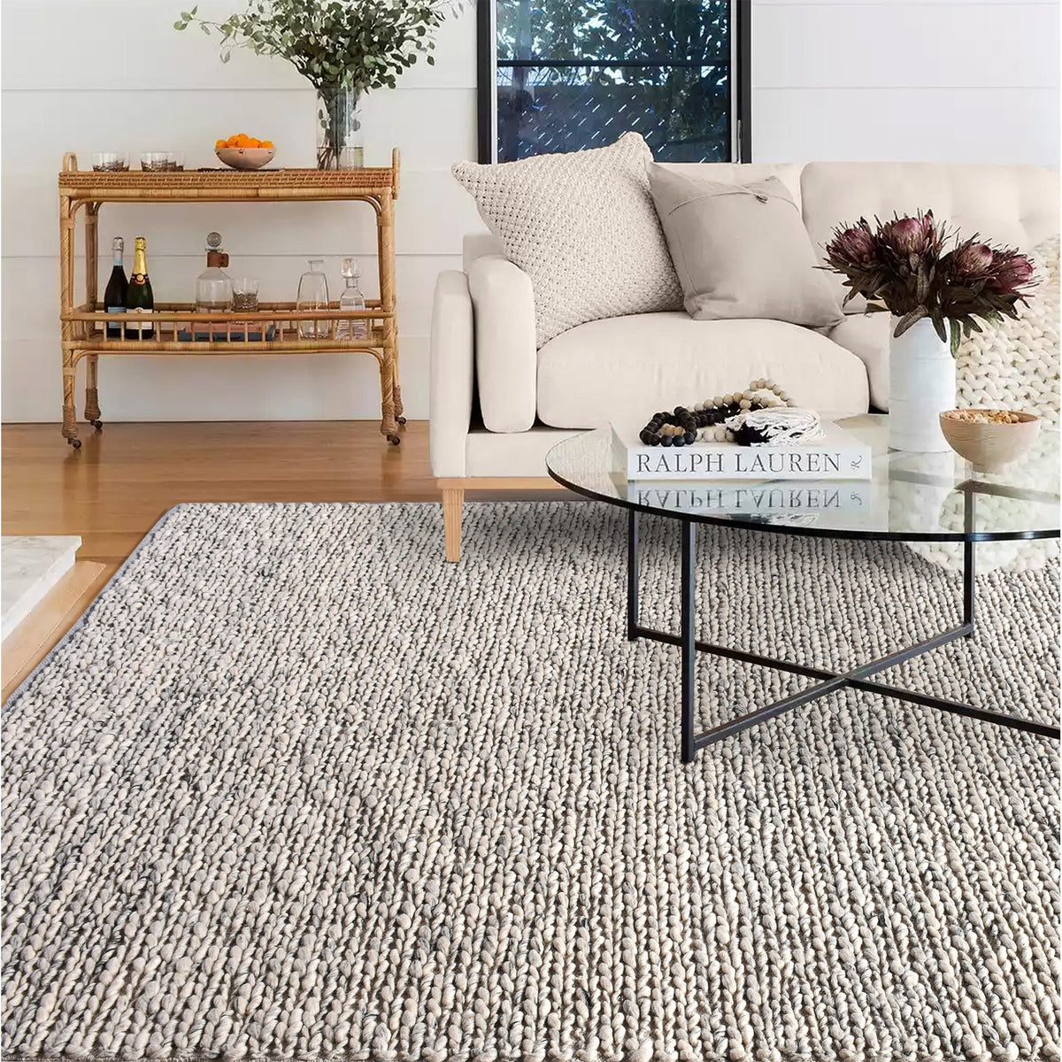 Rassi handwoven wool rug with a chunky braided weave in ivory, oatmeal and grey, in a living room