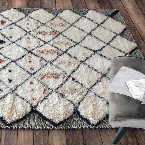 Kesar hand-knotted New Zealand wool shag rug in cream with a black diamond lattice and rust, in a bedroom