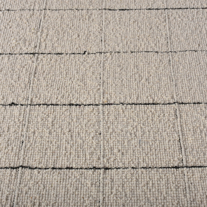Khidki handwoven wool flatweave rug with fine charcoal grid lines on ivory, in a living room