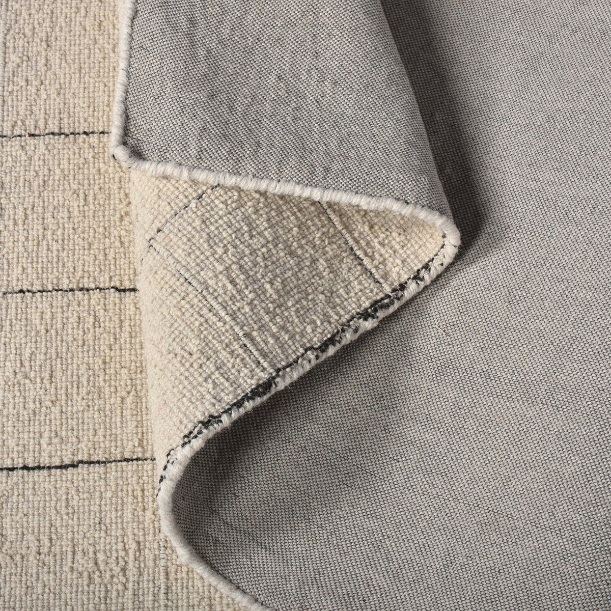Khidki handwoven wool flatweave rug with fine charcoal grid lines on ivory, in a living room