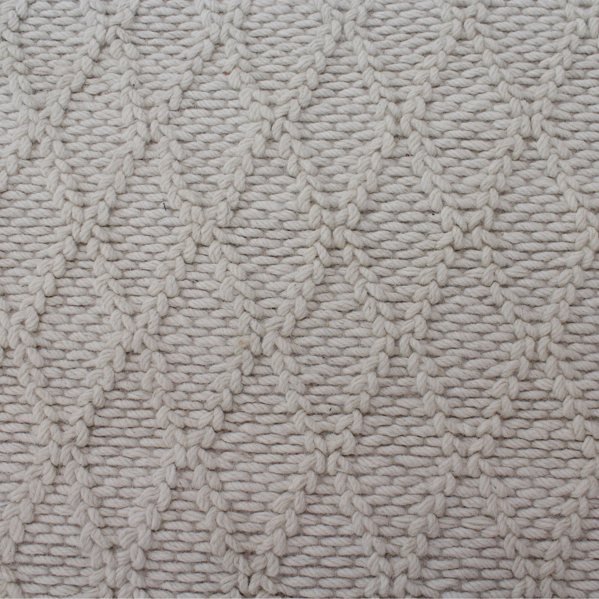 Jaal handwoven ivory wool rug with a raised cabled diamond lattice, in a living room