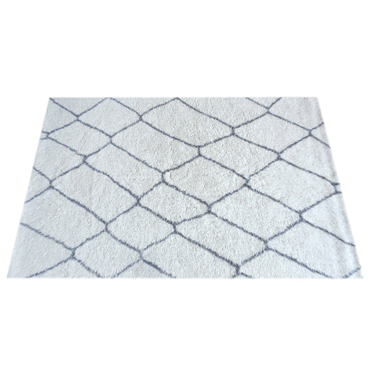 Kohra tufted New Zealand wool rug with a grey diamond lattice on white, in a living room