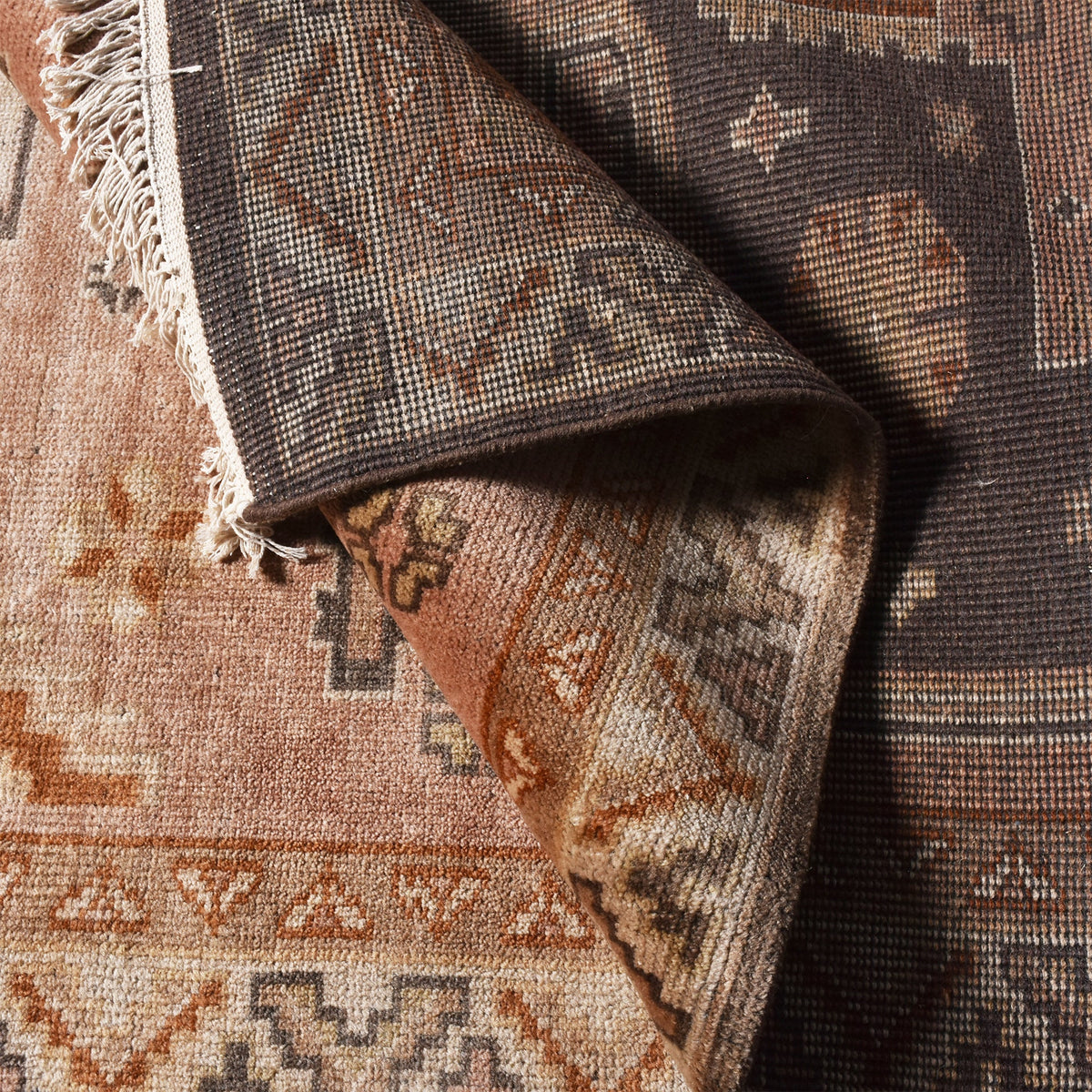 Matka hand-knotted wool rug with a faded terracotta Persian medallion, navy and brown, in a bedroom