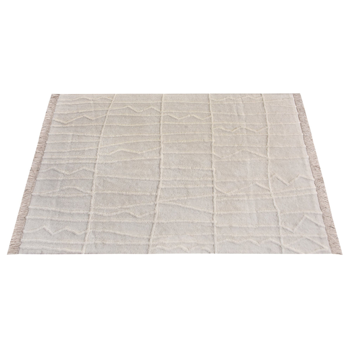 Swell tufted ivory New Zealand wool rug with carved waves and fringe, in a living room