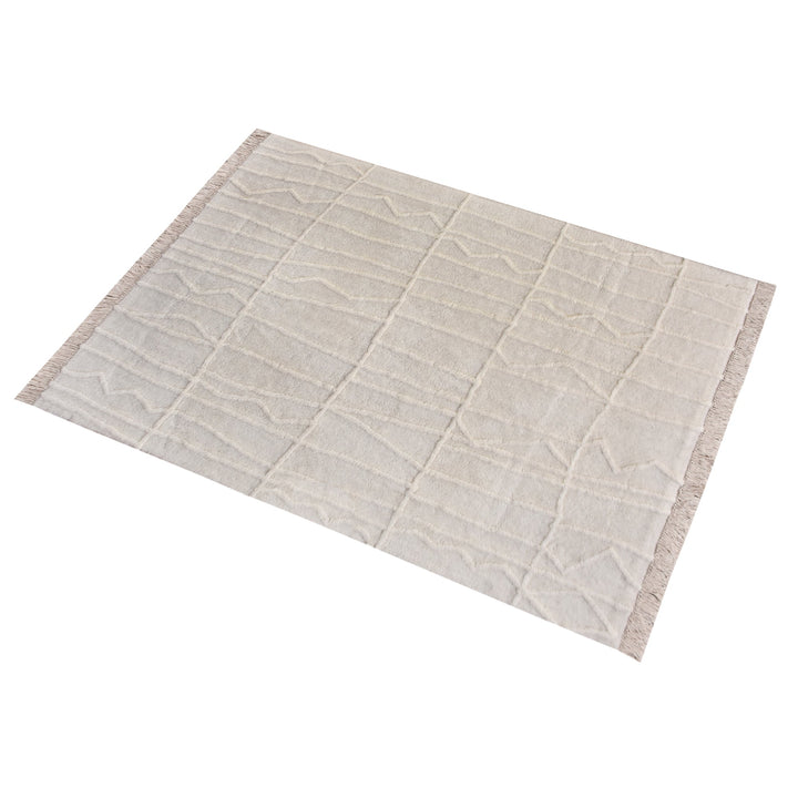 Swell tufted ivory New Zealand wool rug with carved waves and fringe, in a living room