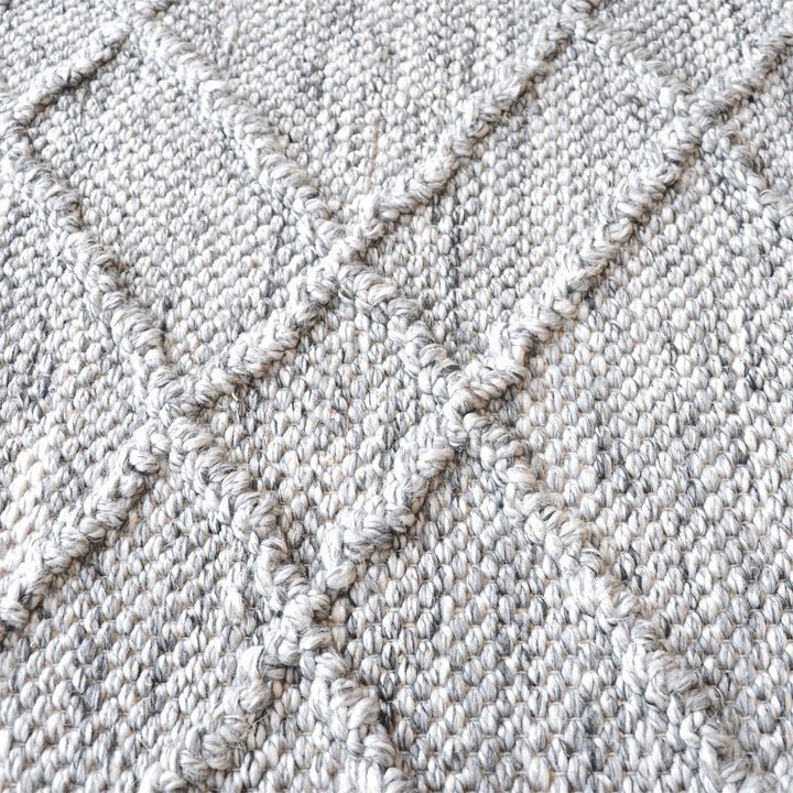 Razai handwoven recycled PET rug with a taupe diamond-quilted raised weave, on a patio