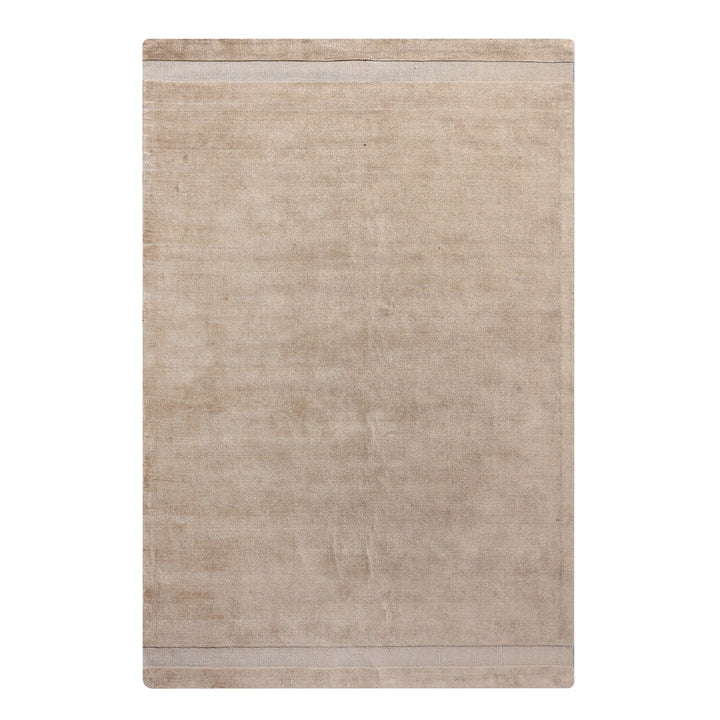 Chamak handwoven viscose rug in plain camel sand with a soft sheen, in a living room
