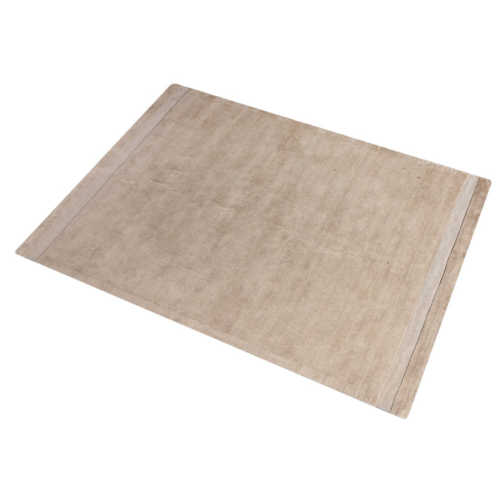 Chamak handwoven viscose rug in plain camel sand with a soft sheen, in a living room