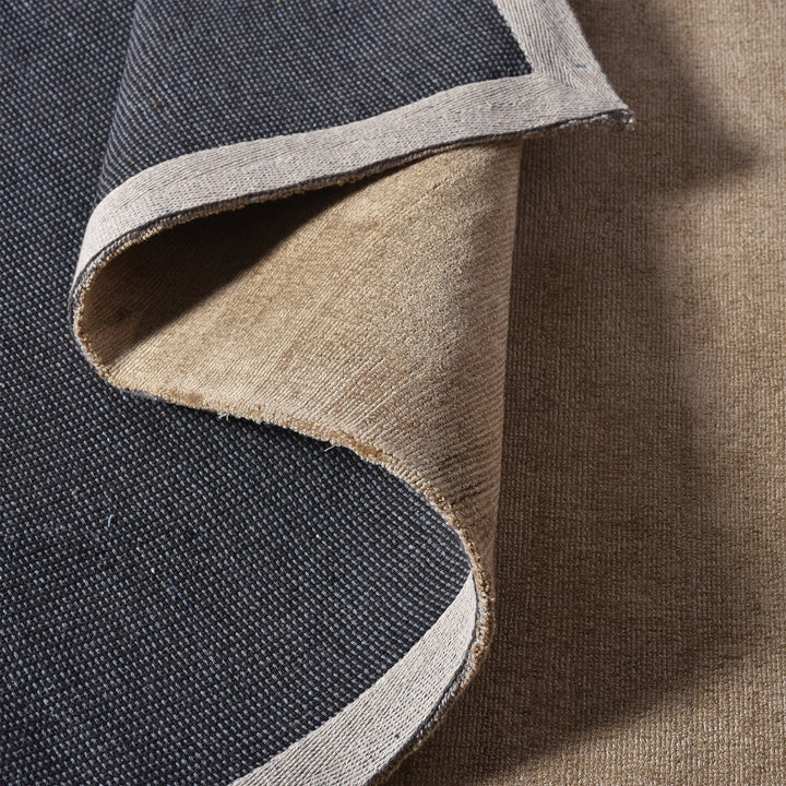 Chamak handwoven viscose rug in plain camel sand with a soft sheen, in a living room