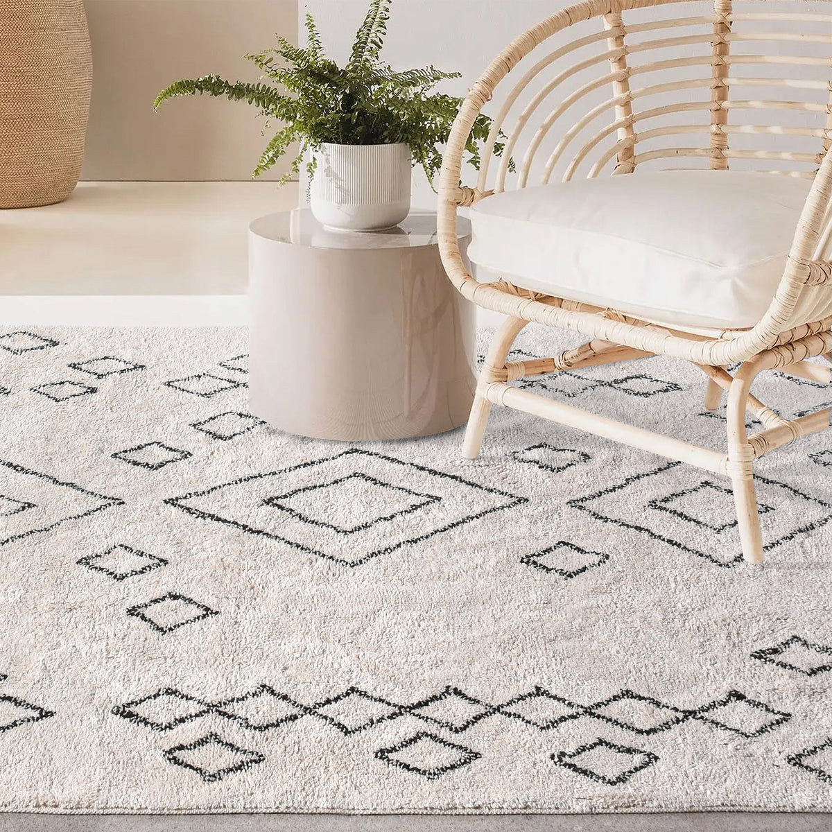 Chhapa tufted cotton rug with black diamonds and chevron borders on bone white, in a study