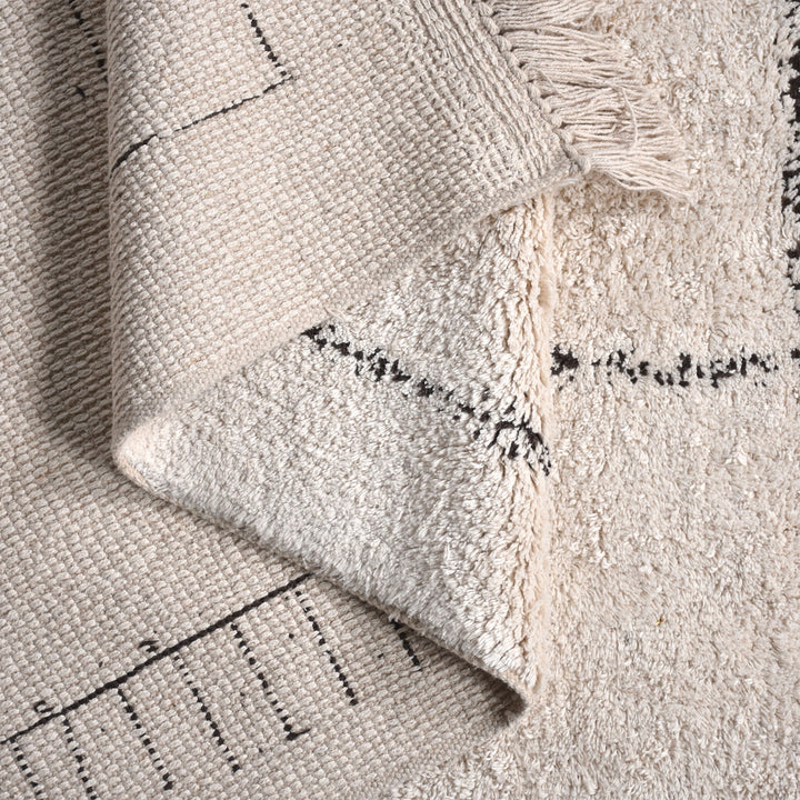 Khaka tufted cotton rug with charcoal outline squares on ivory, in a living room