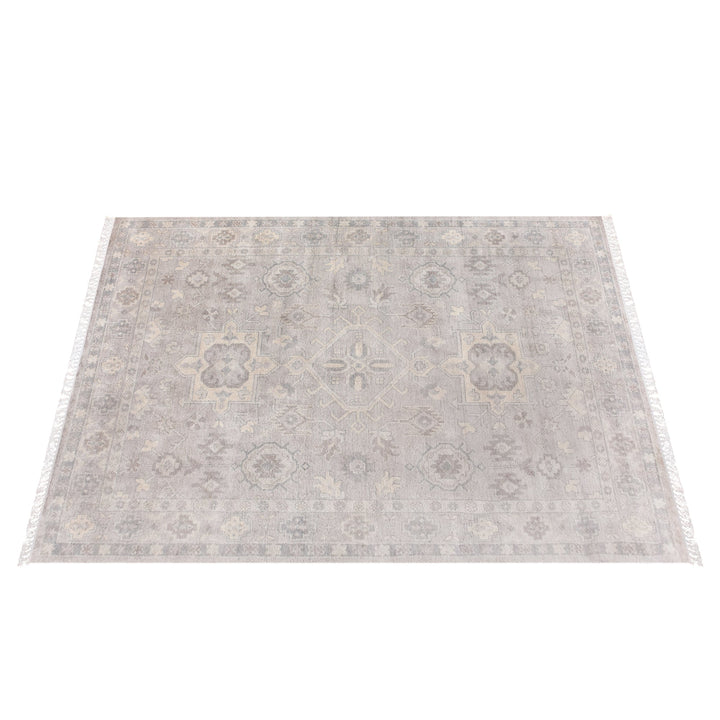Yaad hand-knotted wool rug with distressed tribal medallions in pale taupe and rust, in a dining room