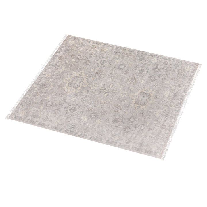 Yaad hand-knotted wool rug with distressed tribal medallions in pale taupe and rust, in a dining room