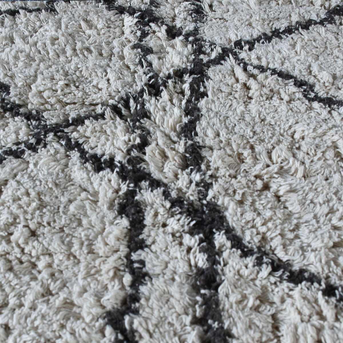 Lipi tufted cotton shag rug in ivory with a bold black lattice, in a bedroom