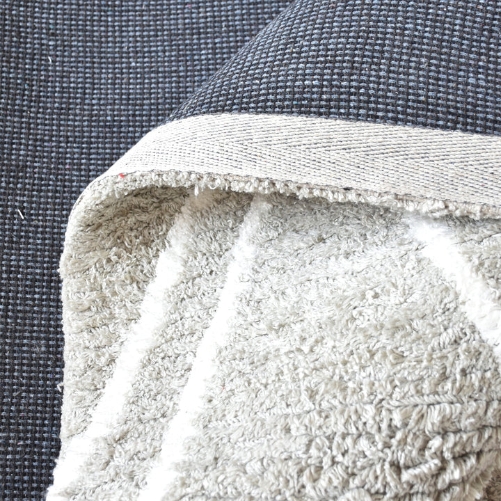 Jugnu tufted cotton and viscose rug with ivory diamond lines on silver grey, in a bedroom
