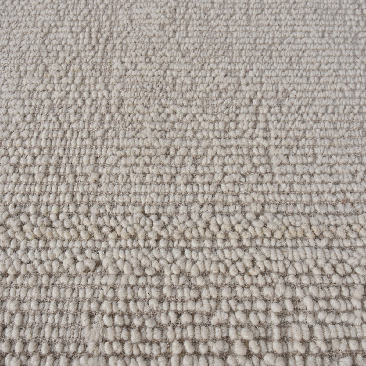 Linen handwoven wool rug in plain cream with a tonal border, in a bedroom