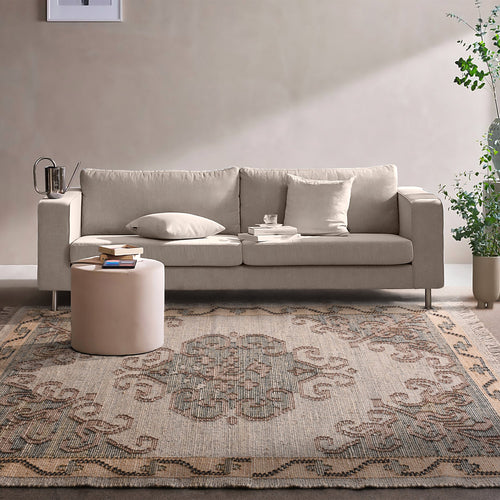 Haveli handwoven flatweave jute and wool rug with a faded beige medallion and terracotta border, in a living room