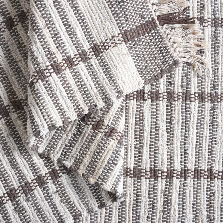 Awning handwoven denim and cotton rug with broad grey and ivory stripes, in a living room
