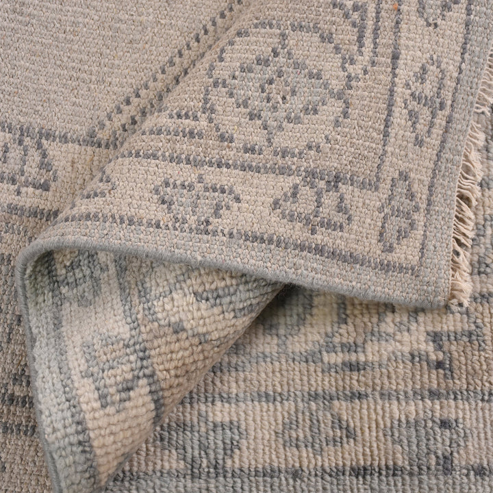 Aab hand-knotted wool rug with a faded blue medallion on an ivory ground, in a living room