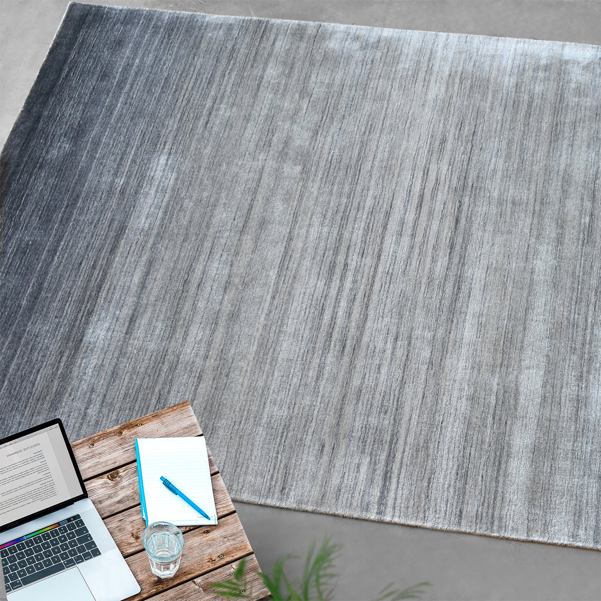 Baadal handwoven wool and viscose rug in streaked grey, charcoal and silver, in a living room