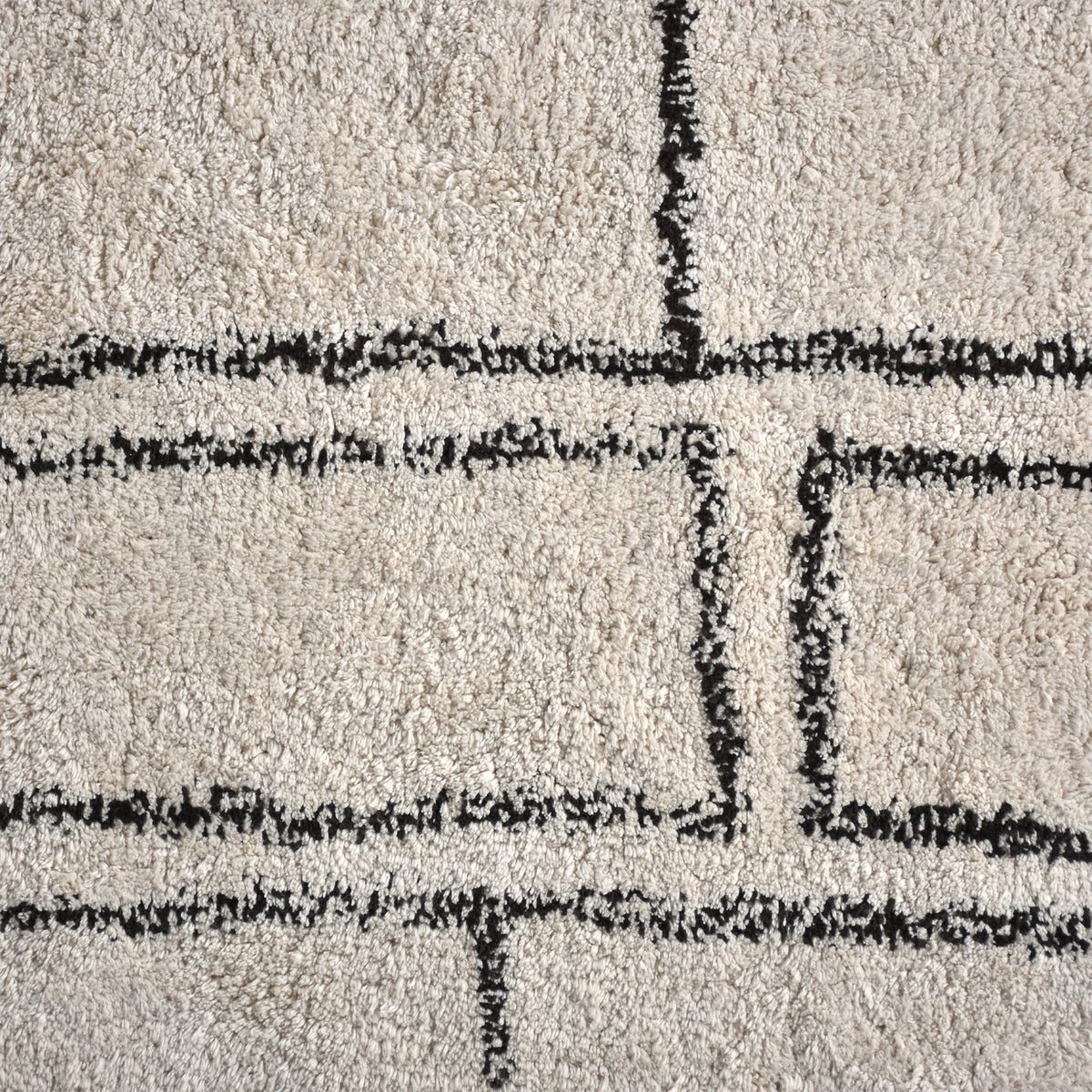 Eent tufted cotton rug with charcoal rectangle grid on ivory, in a bedroom