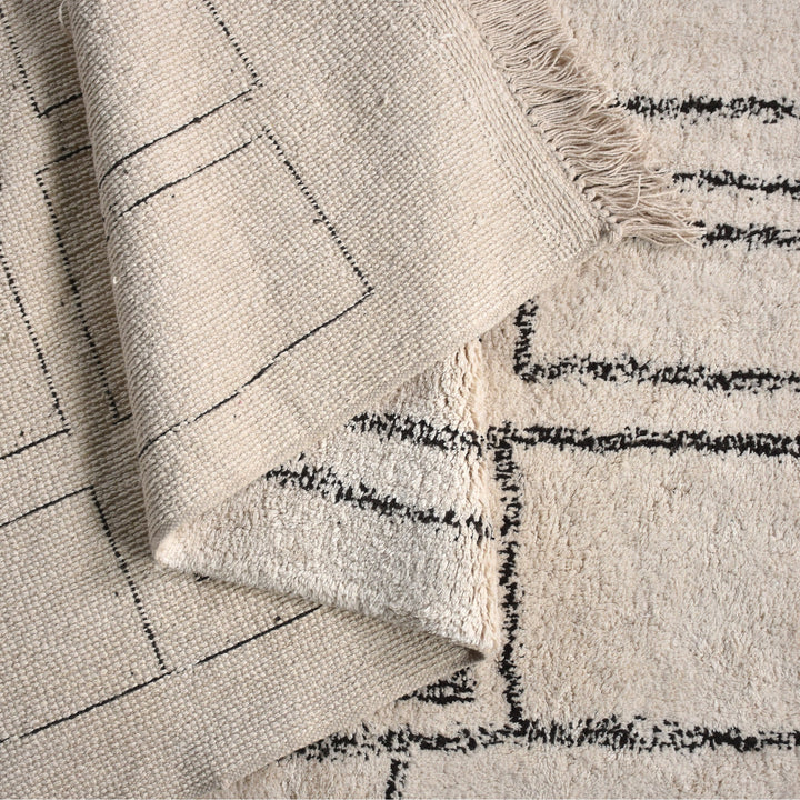 Eent tufted cotton rug with charcoal rectangle grid on ivory, in a bedroom