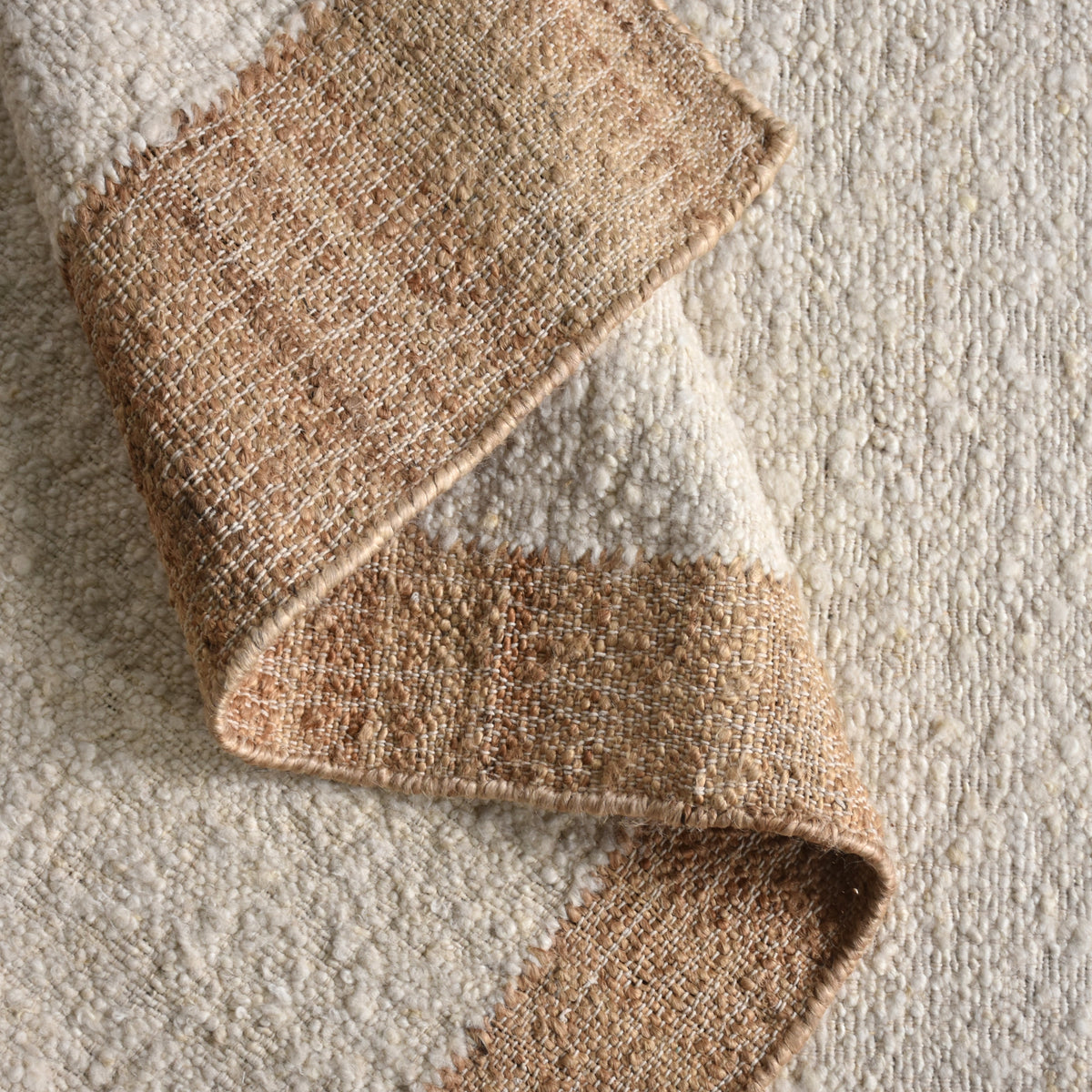 Kinari handwoven wool and jute rug in pale ivory with plain ribs and a tonal border, in a living room