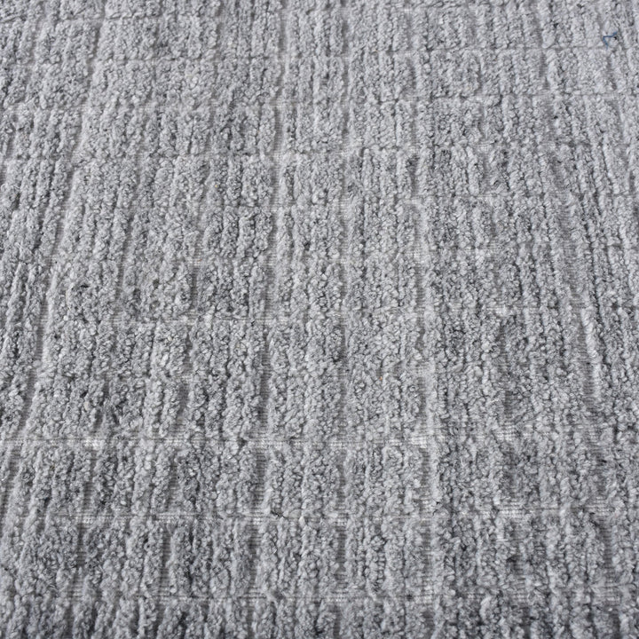 Raakh handwoven flatweave recycled PET rug in plain heather grey with fringe, in a living room