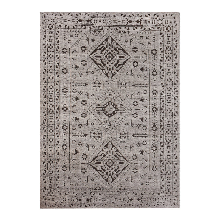 Inkwell hand-knotted ivory wool rug with a faded black tribal medallion, in a living room