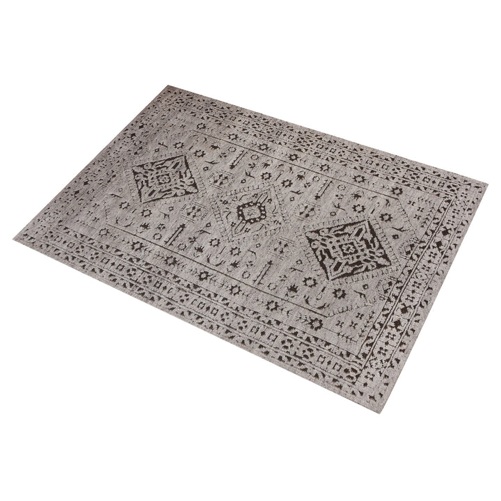 Inkwell hand-knotted ivory wool rug with a faded black tribal medallion, in a living room