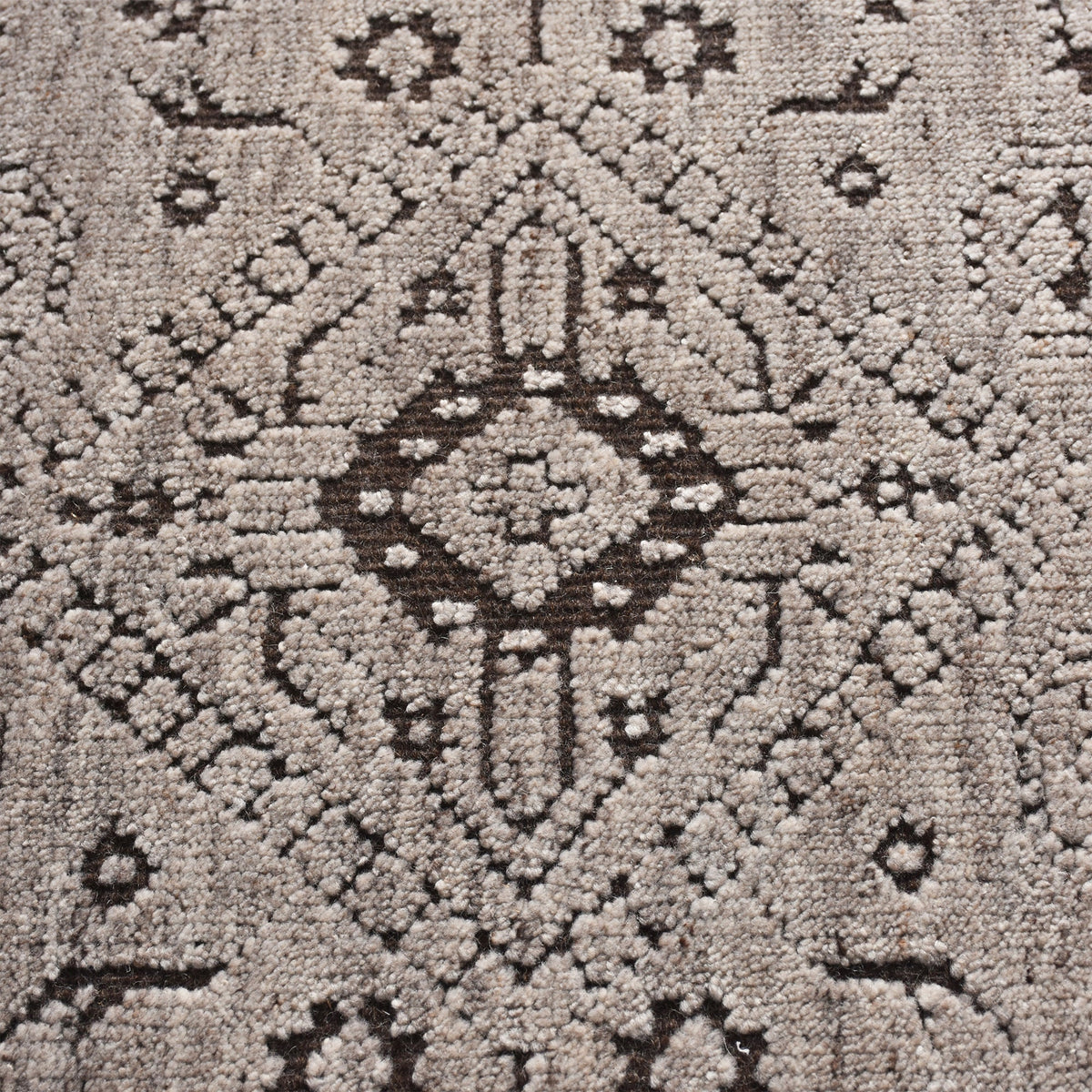 Inkwell hand-knotted ivory wool rug with a faded black tribal medallion, in a living room